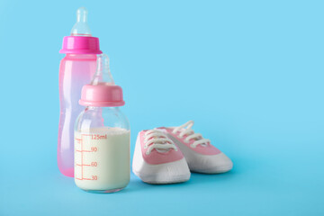 Bottles of milk for baby with booties on blue background