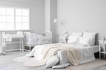 Fototapeta na wymiar Interior of light bedroom with bed, changing table and baby crib