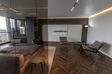 cool expensive interior design of room in prestigious luxury hotel with dark tones with modern LED lighting and stylish furniture. the area with a sink is separated by dark glass from the bedroom