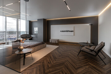 cool expensive interior design of room in prestigious luxury hotel with dark tones with modern LED lighting and stylish furniture. the area with a sink is separated by dark glass from the bedroom