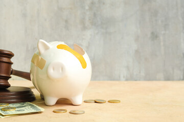 Broken patched piggy bank with judge gavel and money on grunge background. Bankruptcy concept
