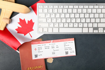 Canadian flag with wooden airplane, passport, ticket and computer keyboard on dark background