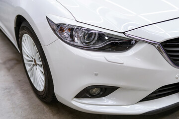 Obraz na płótnie Canvas Protective film sticker on the headlight of a white car. Car detailing studio