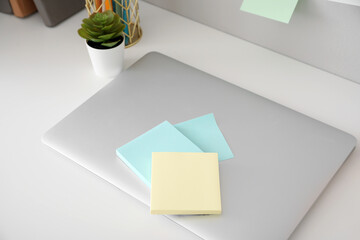 Laptop with sticky notes on white table