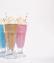 Birthday composition. Copy space for text. Holiday bright creamy milkshakes with colored sprinkles on white background.