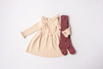 Beige dress and brown leggings for a girl. Children's fashion, children's wardrobe. White background, top view
