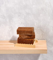 Three brown pieces of natural organic soap for facial and body skin care on a wooden soap dish in the shape of a lattice. Copy space for text.