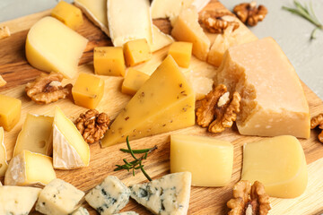 Wooden board with pieces of tasty cheese on table, closeup