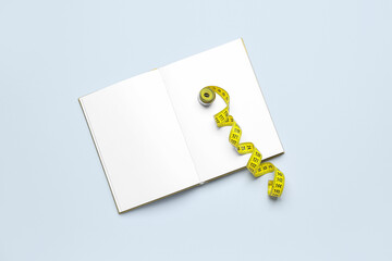 Blank open notebook and measuring tape on light background