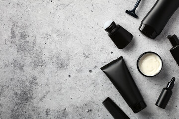 Black tubes and bottles with men's cosmetics on stone table. Flat lay, top view.