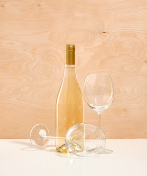 A composition of one beautiful bottle of white wine and two glasses on wooden background. Romantic dinner or lunch.