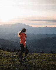 Fototapeta premium Girl with warm clothes walks through the Urkiola mountain in a sunset of warm lights but very cold