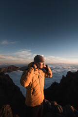 Young man bundles up while watching the beautiful sunset over Caldera De Taburiente from the top of Roque De Los Muchachos