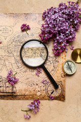 Fototapeta na wymiar World map with compass, magnifier and lilac flowers on beige grunge background