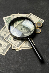 Magnifier with one hundred dollars on grunge black background