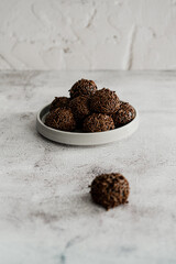 Foto minimalista de brigadeiros de chocolate com granulado empilhados com fundo branco e textura com espaço para texto