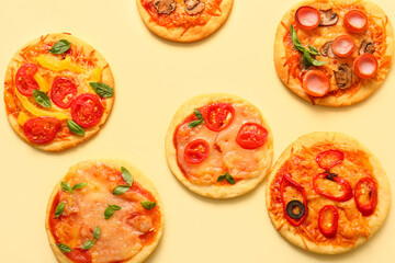 Different tasty mini pizzas on yellow background