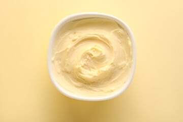 Bowl with tasty cream cheese on yellow background