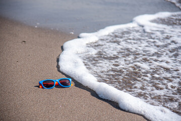Obraz premium Colored sunglasses abandoned on the sandy beach by the seaside
