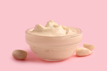 Bowl with tasty cream cheese on pink background
