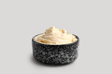 Bowl with tasty cream cheese on grey background