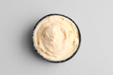 Bowl with tasty cream cheese on grey background