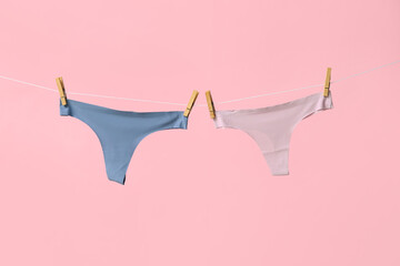 Female panties hanging on rope against pink background