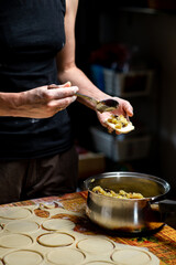 Preparation of varines. Unrecognizable woman puts filling in dough. Sculpting dumplings.