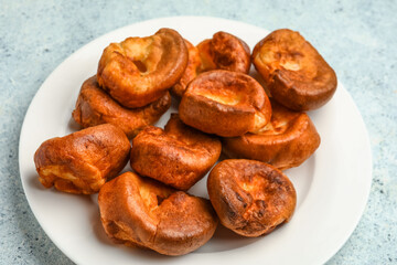 Plate with tasty Yorkshire pudding on light background