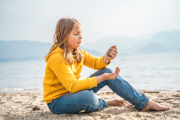 Lonely beautiful sad girl teenager sits thoughtfully on sand sea beach. Dreams,anxiety,worries...