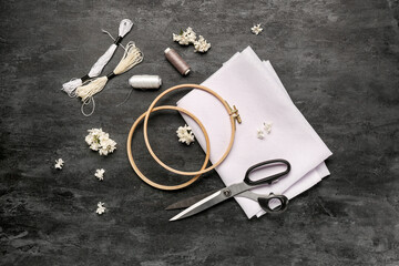 Embroidery hoops with canvas, mouline threads and scissors on grunge black background © Pixel-Shot