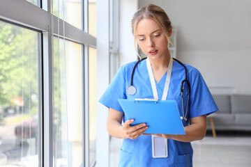 Female medical intern with clipboard in clinic