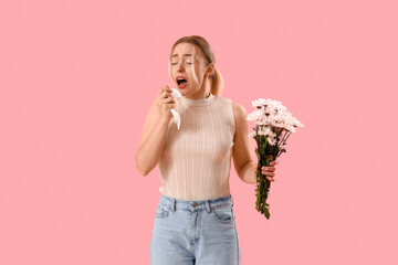Allergic young woman with flowers on pink background