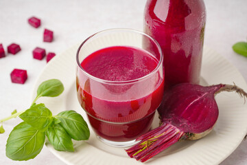 Glass and bottle of fresh beetroot juice on light background