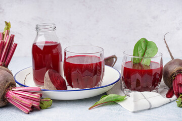 Glasses and bottle of fresh beetroot juice on light background