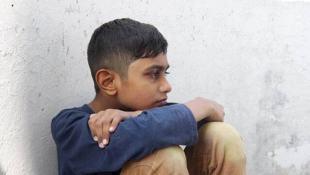 Young afro boy sitting alone with sad feeling. School Bullying, Discrimination and racism concept. A sad kid. Childhood loneliness. Child abuse.