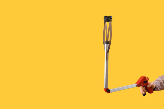 Female hand holding long reach grabber tool on yellow background