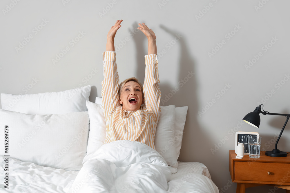 Wall mural Mature woman waking up in bed