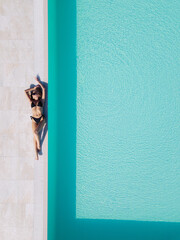 a girl in a black swimsuit lies by the pool. view from a copter.