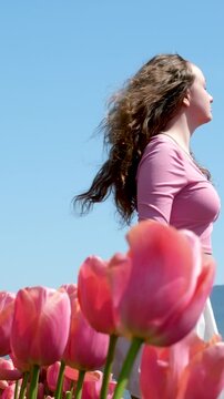 young teen woman stands in polis with pink tulips look into distance look into future look into nowhere Freedom purity freshness wind develop 