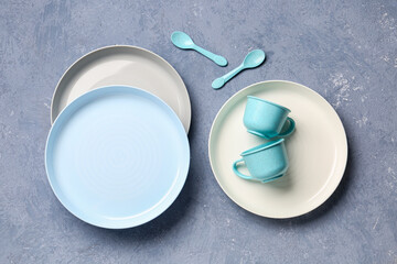 Plates with cups and spoons for baby on grunge blue background