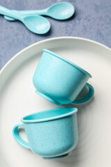 Plate with cups and spoons for baby on grunge blue background