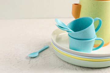 Plates with cups, teapot and spoons for baby on white table