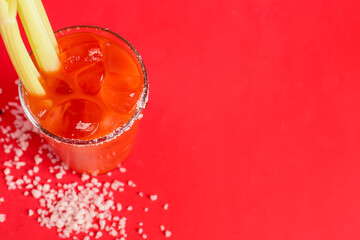 Glass of bloody mary with celery and salt on red background - obrazy, fototapety, plakaty