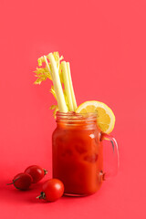 Mason jar of bloody mary with celery and lemon on red background © Pixel-Shot
