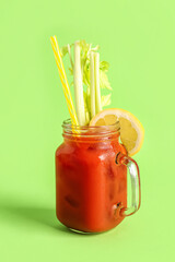 Mason jar of bloody mary with celery and lemon on green background © Pixel-Shot