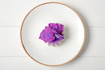 Plate of panna cotta with beautiful hydrangea flowers on white wooden table