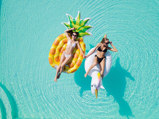 lgbt couple drinking and hugging each other in swimming pool, view from above