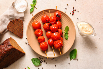 Plate of skewers with tasty grilled tomatoes and basil on white background