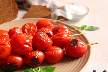Plate of skewers with tasty grilled tomatoes and basil on white background